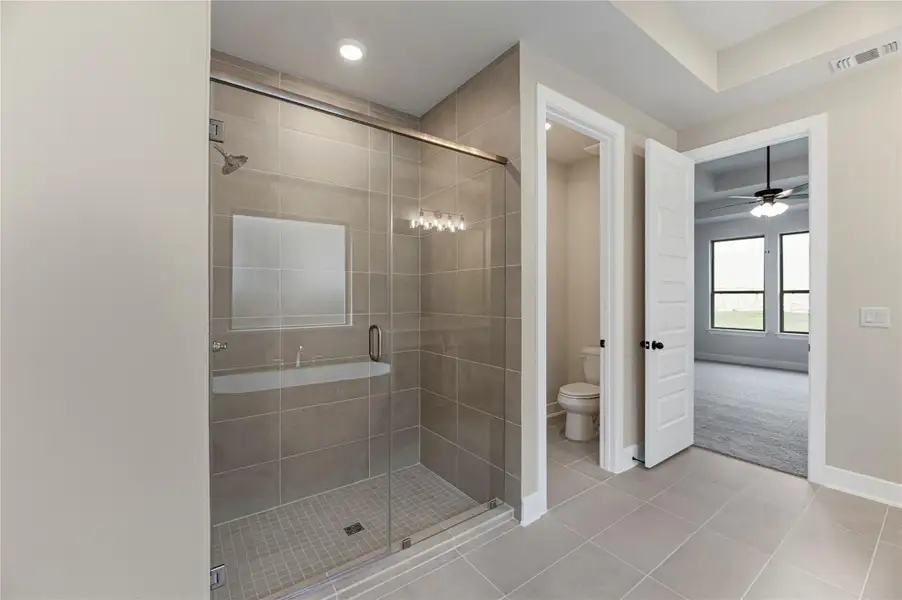 Bathroom with a stall shower, tile patterned flooring, and a ceiling fan
