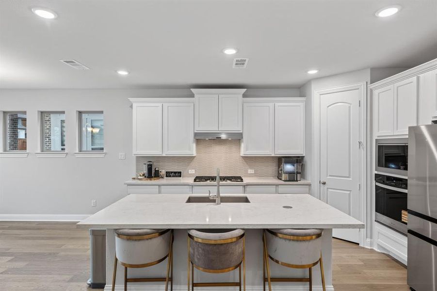 Kitchen with light stone counters, a breakfast bar area, stainless steel appliances, a kitchen island with sink, and recessed lighting Kitchen with light stone counters, a breakfast bar area, stainless steel appliances, a kitchen island with sink, and recessed lighting