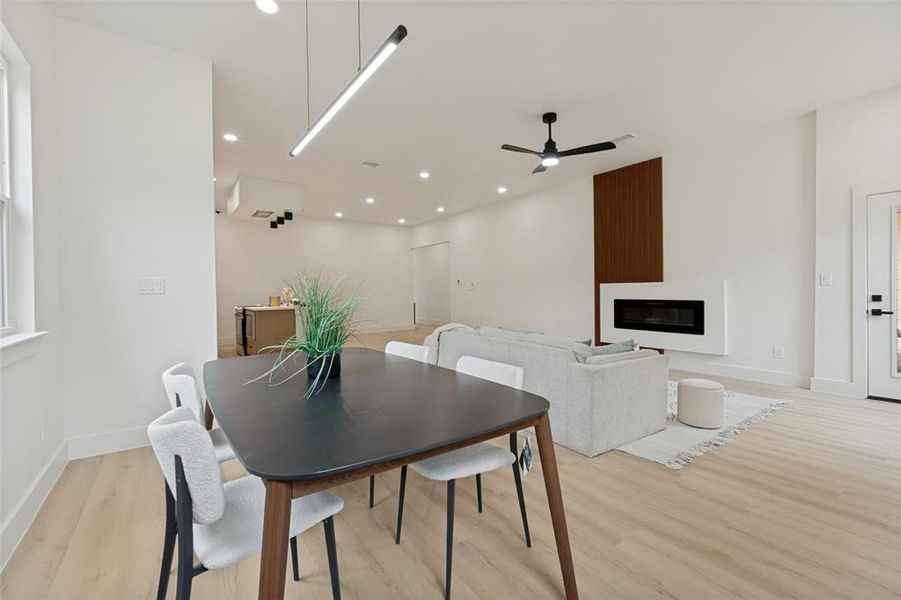 Open-concept living area featuring light wood-finish flooring, recessed lighting, and a linear pendant light fixture