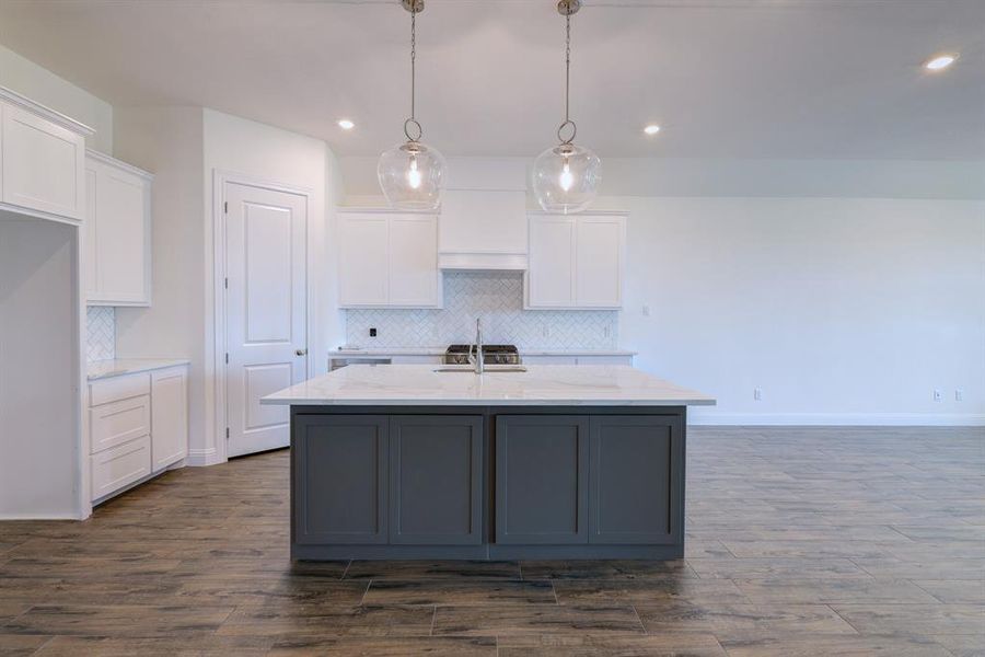 Kitchen featuring recessed lighting, white cabinetry, tasteful backsplash, a center island with sink, and dark wood finished floors