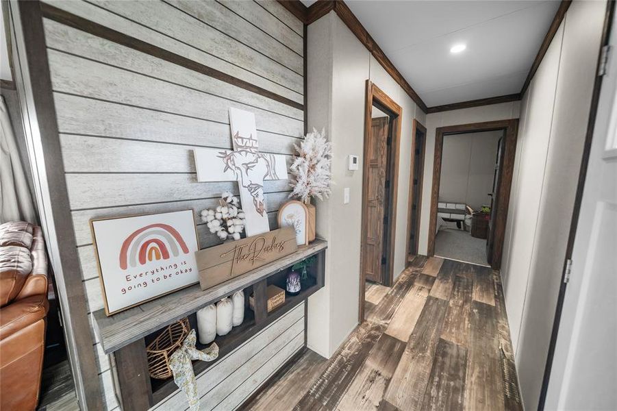 Hallway with dark wood-style floors, ornamental molding, wood walls, and recessed lighting Hallway with dark wood-style floors, ornamental molding, wood walls, and recessed lighting