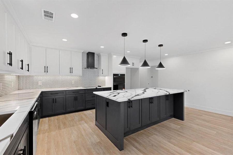 Kitchen featuring dark cabinets, white cabinetry, black appliances, light stone countertops, and hanging light fixtures