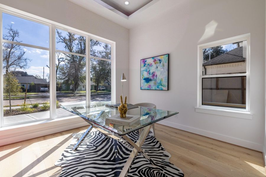 Alternate view of the first-floor bedroom currently staged as a home office, featuring front-facing windows that bring in abundant natural light.