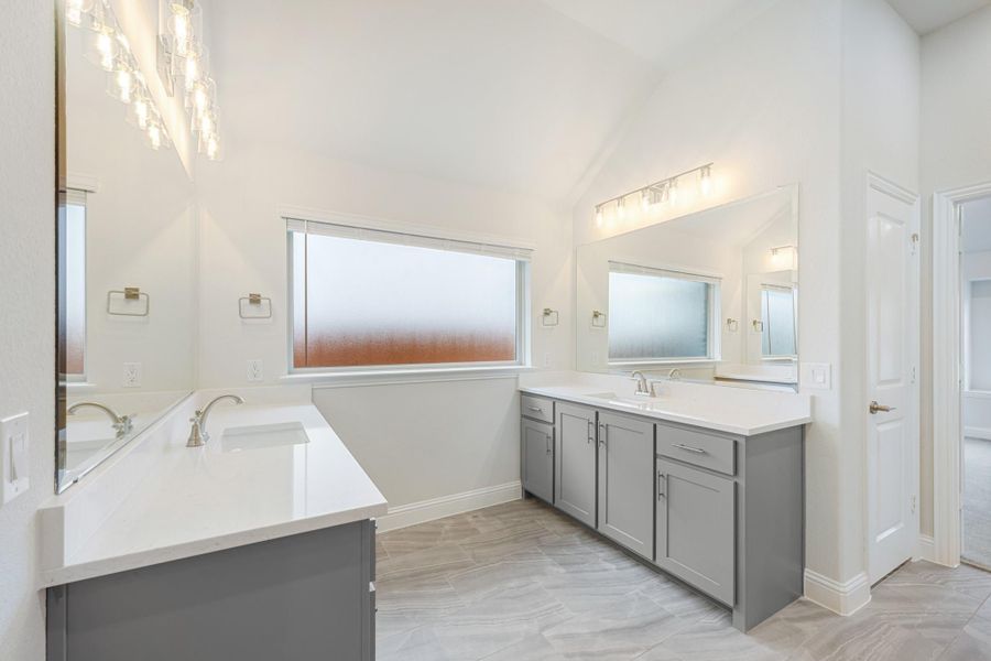 Spacious master bathroom with dual vanities, gray cabinets, white countertops, and vaulted ceiling Spacious master bathroom with dual vanities, gray cabinets, white countertops, and vaulted ceiling