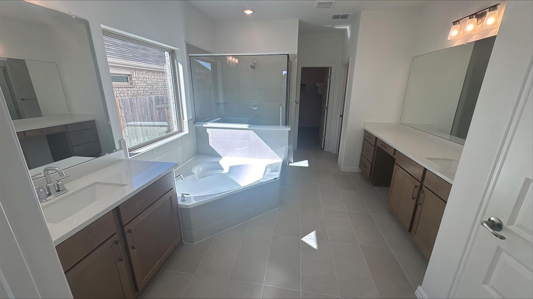 Bathroom featuring a shower stall, light tile patterned flooring, a garden tub, and two vanities
