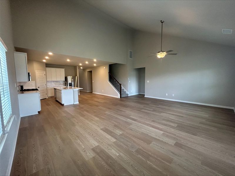 Unfurnished living room with high vaulted ceiling, stairway, ceiling fan, wood finished floors, and recessed lighting Unfurnished living room with high vaulted ceiling, stairway, ceiling fan, wood finished floors, and recessed lighting