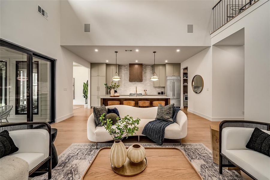 Living room featuring a towering ceiling, light wood-style flooring, and recessed lighting Living room featuring a towering ceiling, light wood-style flooring, and recessed lighting