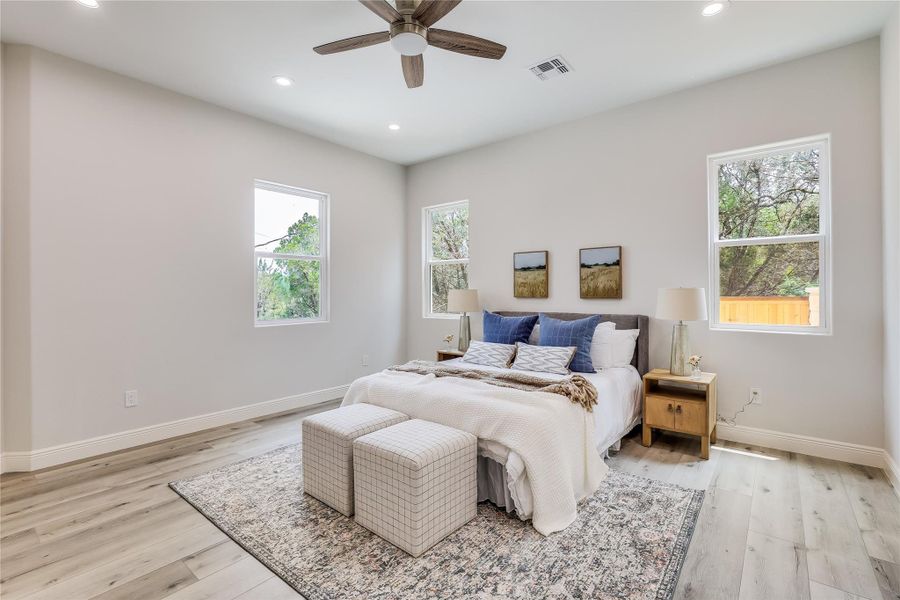 Bedroom featuring ceiling fan, light wood-type flooring, and multiple windows