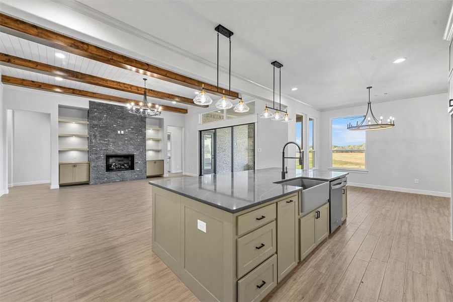 Kitchen with beam ceiling, dishwasher, hanging light fixtures, a center island with sink, and light wood-type flooring