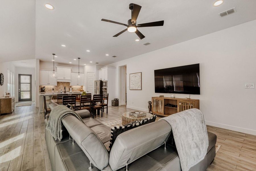 Living room with a ceiling fan, recessed lighting, and light wood-style floors