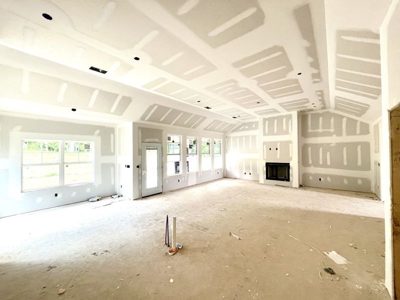 From the back wall of kitchen looking across the Great Room.These 11.5 ft tall ceilings and the wall of windows give this room a wonderful open feel. Note gas fireplace