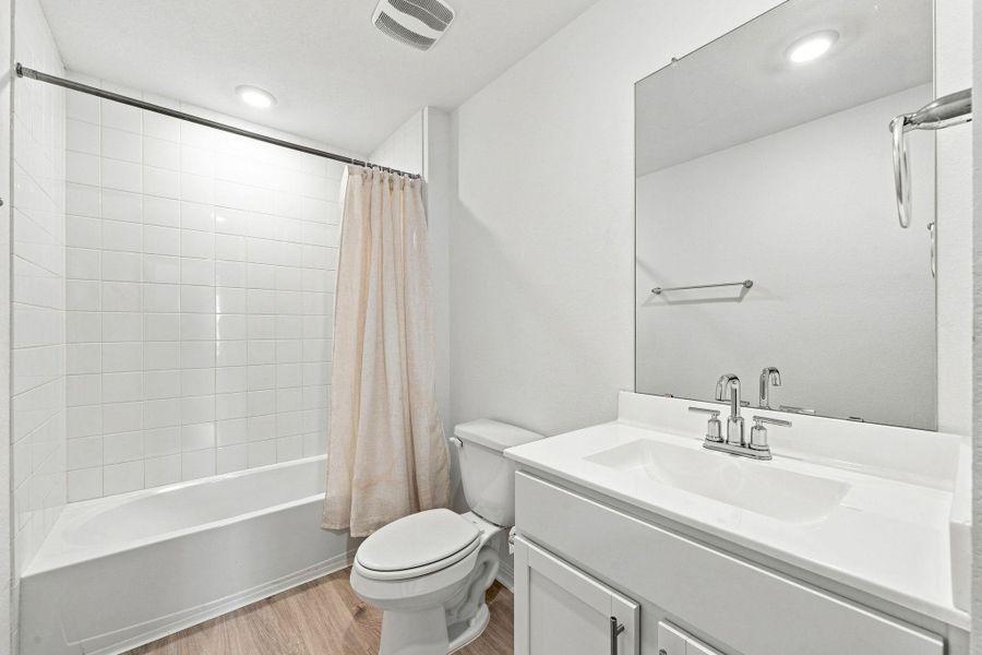 Crisp white tiled tub and shower surround paired with a modern single vanity and neutral flooring.