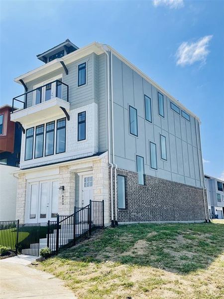 View of front of home with a balcony, a front yard, and stone siding View of front of home with a balcony, a front yard, and stone siding