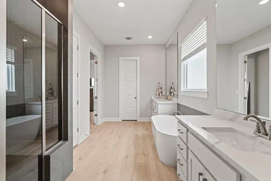 Full bathroom featuring a soaking tub, two vanities, light wood-style floors, and recessed lighting Full bathroom featuring a soaking tub, two vanities, light wood-style floors, and recessed lighting