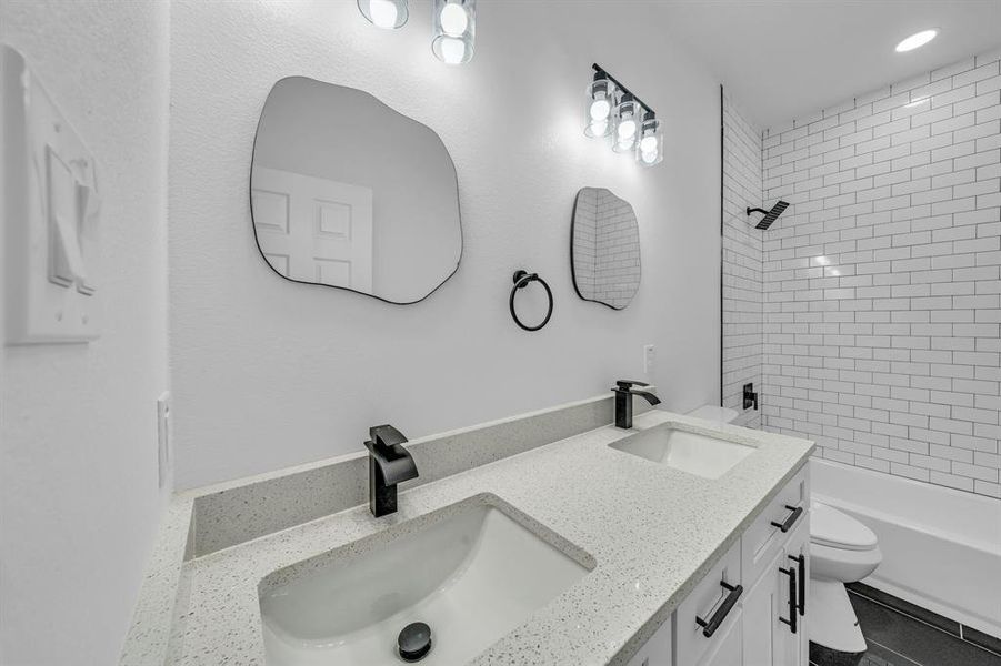 Full bathroom with vanity, tiled shower / bath, and toilet