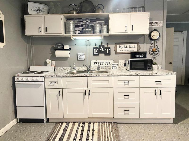 Bar with electric stove, white cabinets, light countertops, and open shelves Bar with electric stove, white cabinets, light countertops, and open shelves