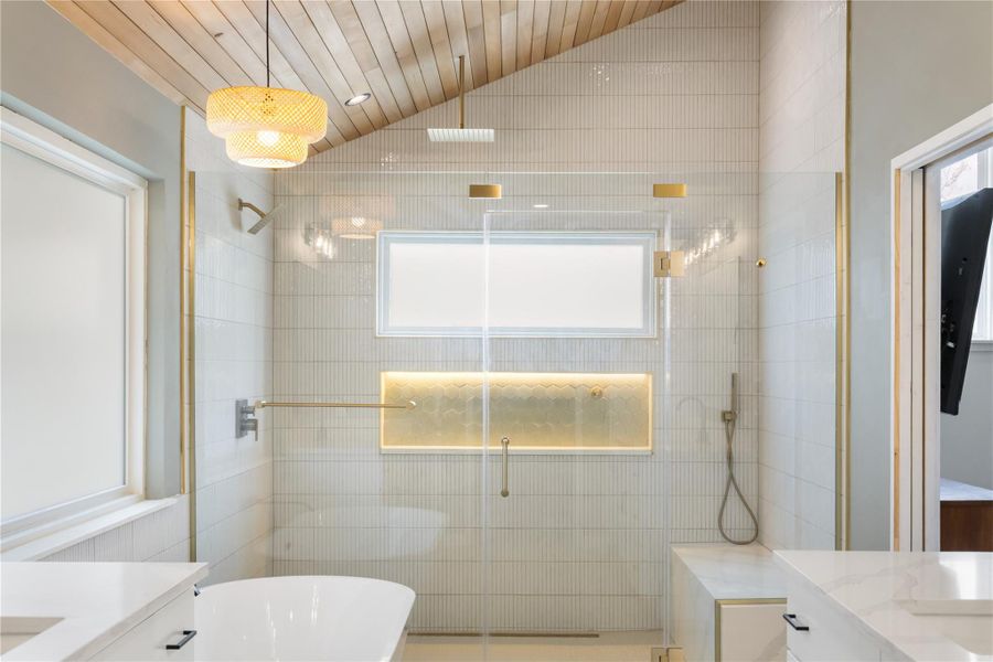 Full bathroom featuring vanity, lofted ceiling, a stall shower, healthy amount of natural light, and a freestanding tub