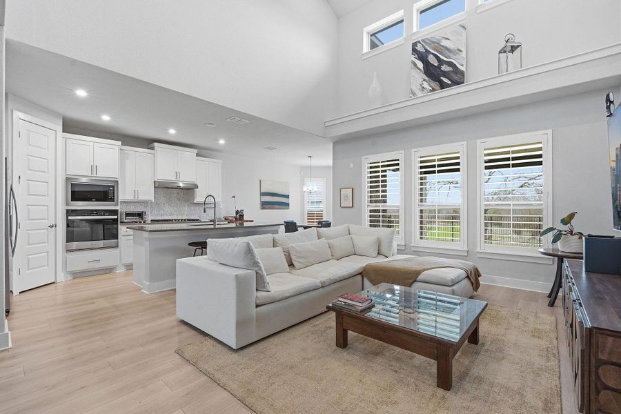 Living area with light wood-type flooring, a high ceiling, and recessed lighting