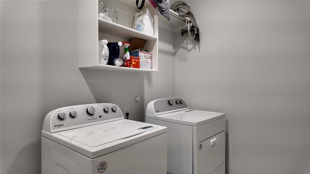 Utility room featuring white walls, a white overhead shelf, and a clothing rod