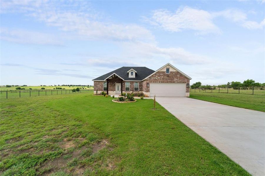 View of front of property with a garage, a rural view, and a front yard