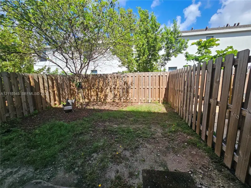 Fenced backyard featuring wood-plank privacy fencing and mature trees