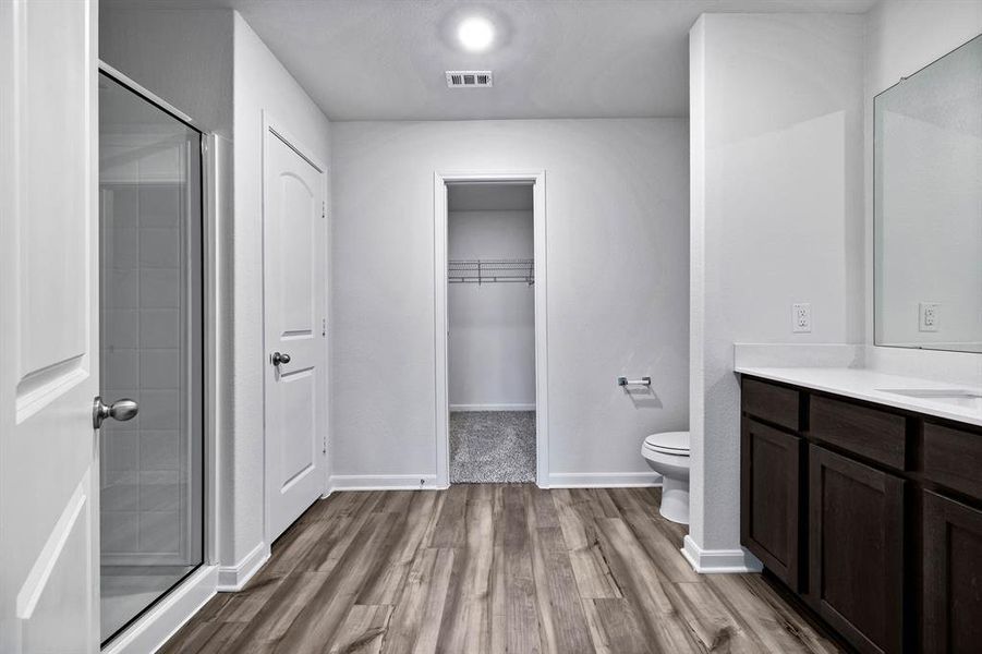 Bathroom with a shower with shower door, vanity, toilet, and hardwood / wood-style floors