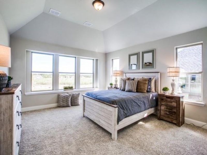 Bedroom with light colored carpet and lofted ceiling