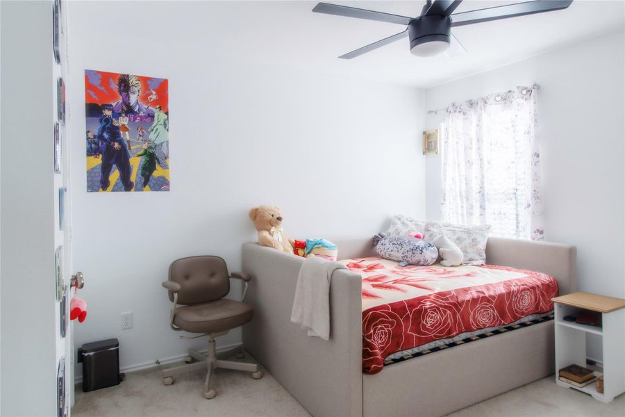 Generous secondary bedroom filled with natural light, neutral carpet, and a ceiling fan—perfect for comfort and versatility.