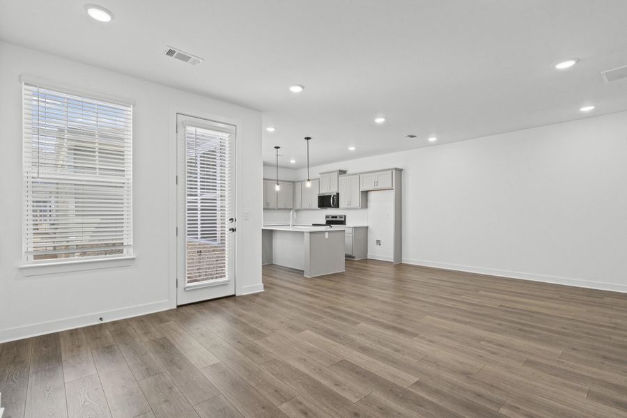 Open-concept living space featuring wood-finish flooring, recessed lighting, and a glass-paneled door