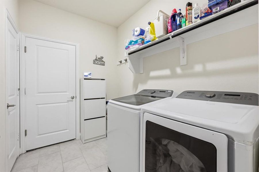 Dedicated laundry area featuring light-toned tile flooring, white walls, and a built-in storage shelf with hanging rod
