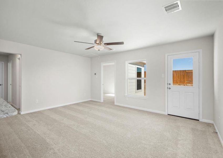 A cozy carpeted living room with a door that leads to the back yard.