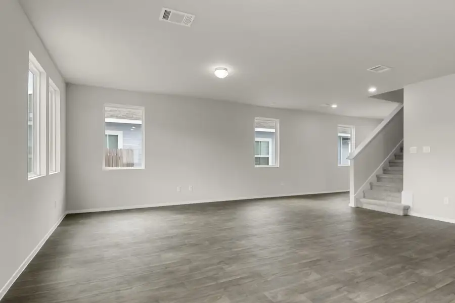 Image of a two story home living room with a staircase and windows