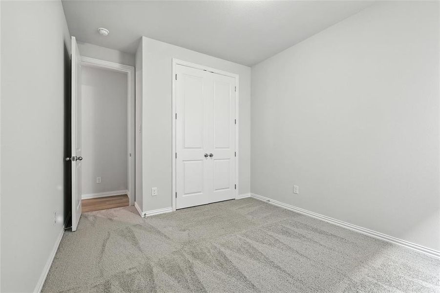Unfurnished bedroom with light colored carpet and a closet