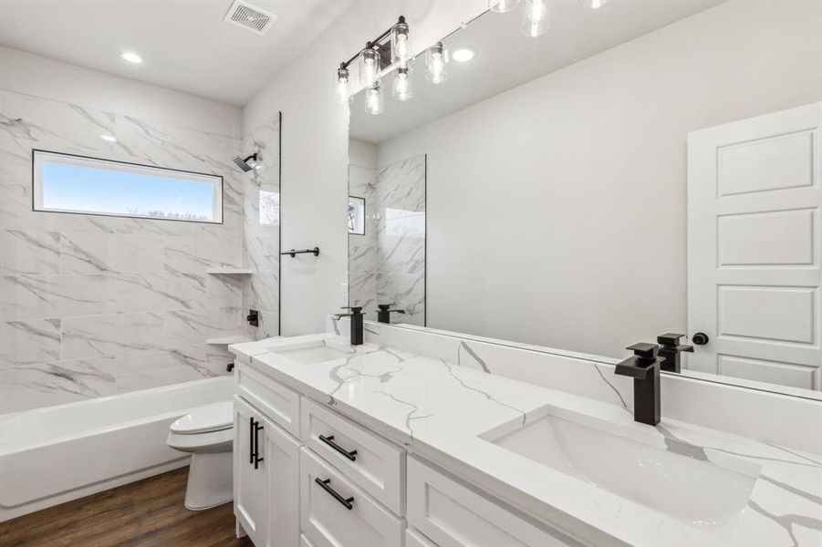 Full bathroom featuring hardwood / wood-style floors, toilet, vanity, and tiled shower / bath