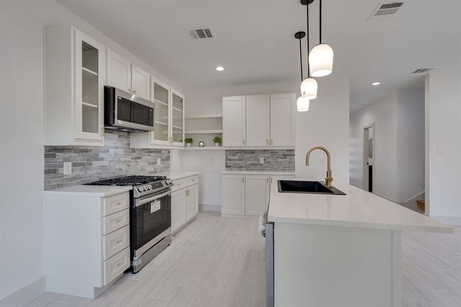 Kitchen featuring sink, backsplash, white cabinetry, and stainless steel appliances