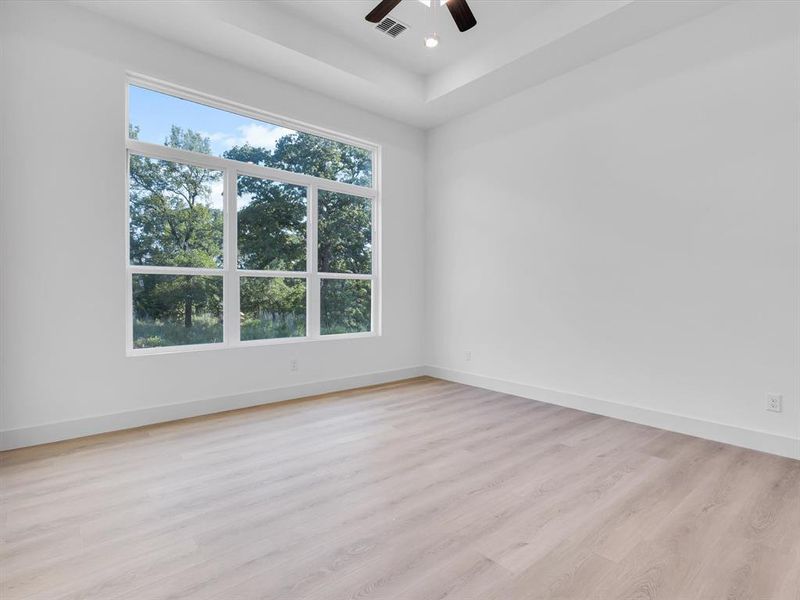 Unfurnished room featuring light wood finished floors, a tray ceiling, ceiling fan, and recessed lighting Unfurnished room featuring light wood finished floors, a tray ceiling, ceiling fan, and recessed lighting