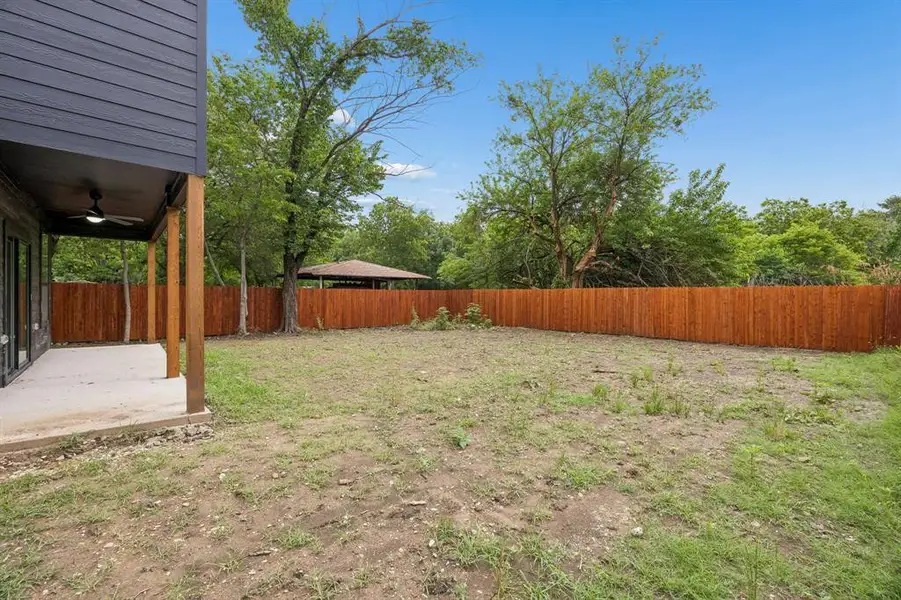 Expansive backyard featuring a new wood privacy fence, concrete patio, and mature trees Expansive backyard featuring a new wood privacy fence, concrete patio, and mature trees