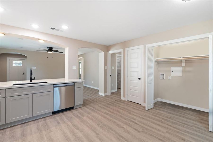 Kitchen with arched walkways, gray cabinetry, stainless steel dishwasher, ceiling fan, and recessed lighting