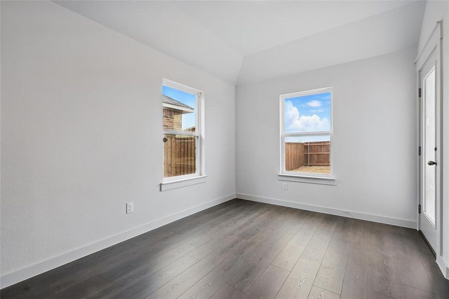 Empty room with dark wood-style flooring and vaulted ceiling Empty room with dark wood-style flooring and vaulted ceiling