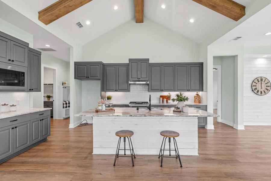 The durable LVP flooring and sophisticated gray-and-white color palette flow right into the Kitchen, creating a cohesive and upscale design aesthetic. Thoughtfully appointed with a decorative tile backsplash, elegant granite countertops, and a shiplap-accented Kitchen island, this beautifully crafted space strikes the perfect balance between style and functionality.