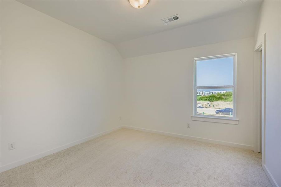 Empty room featuring light carpet and lofted ceiling Empty room featuring light carpet and lofted ceiling