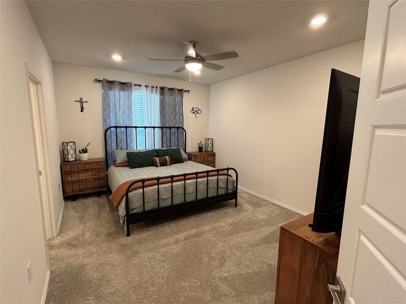 Spacious primary bedroom with carpet, ceiling fan, and recessed lighting Spacious primary bedroom with carpet, ceiling fan, and recessed lighting