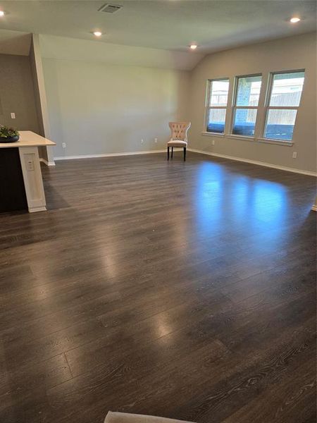 Spare room with dark wood-type flooring and lofted ceiling