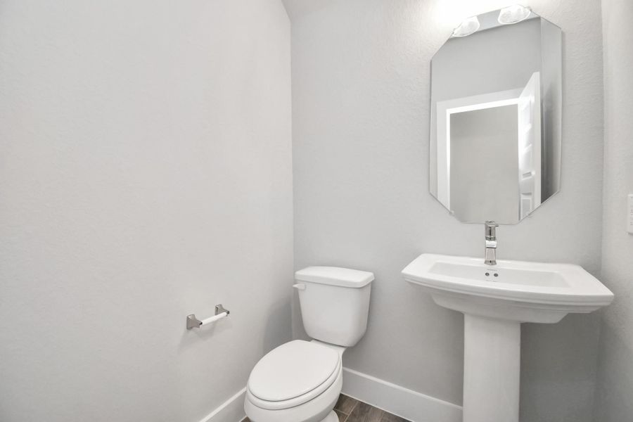 This half bathroom features a stylish pedestal sink, modern hardware, and bright recessed lighting, creating a sleek and inviting space. Sample photo of completed home with similar floor plan. Actual colors and selections may vary.
