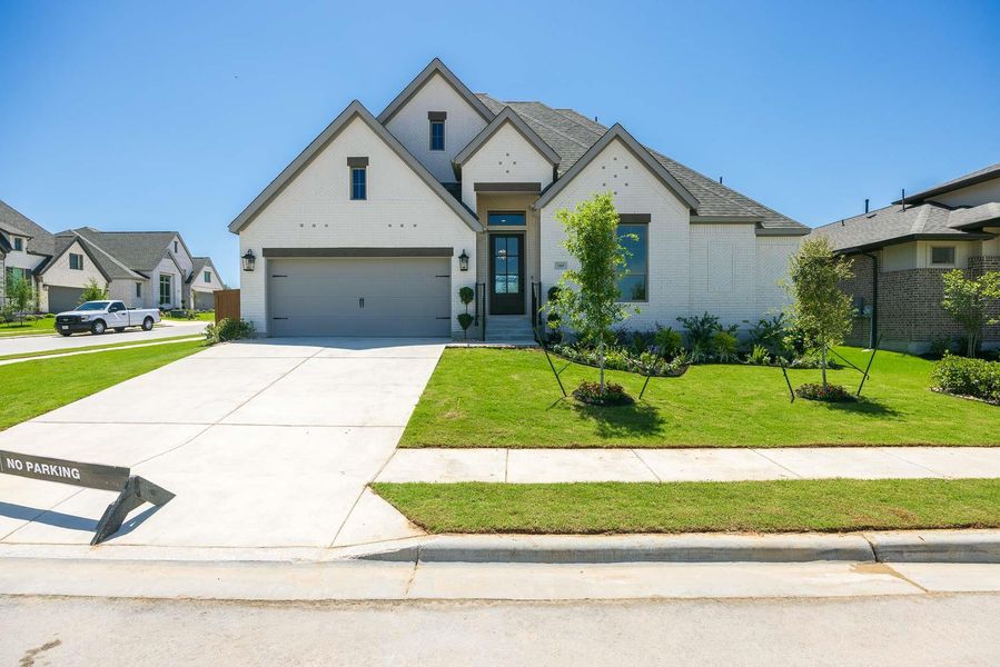 French country style house featuring concrete driveway, a front yard, brick siding, and an attached garage French country style house featuring concrete driveway, a front yard, brick siding, and an attached garage