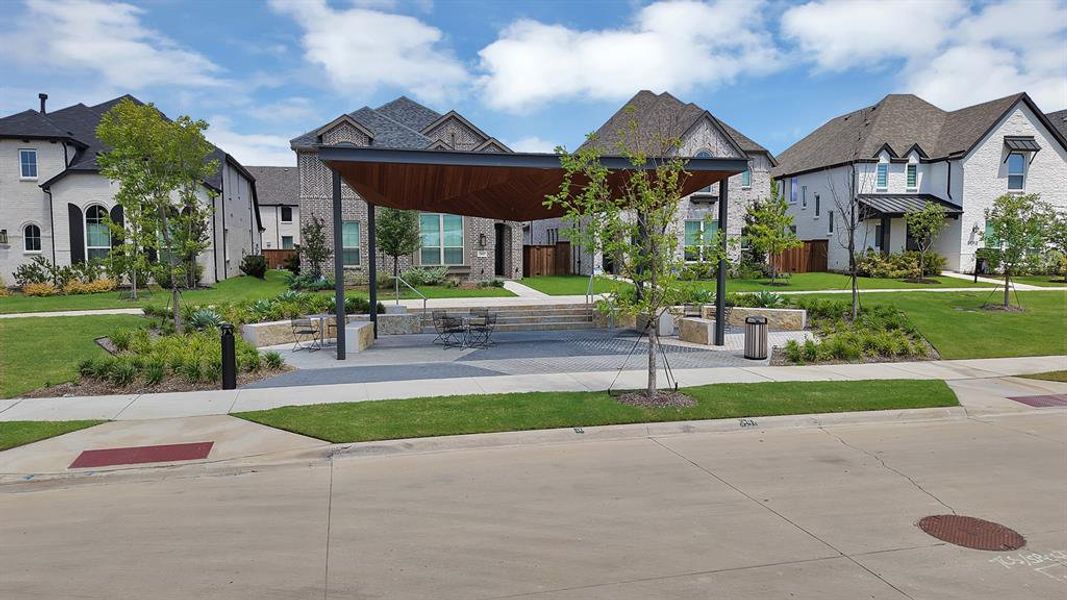 Community gathering space featuring a modern pergola, paved seating area, and integrated planters