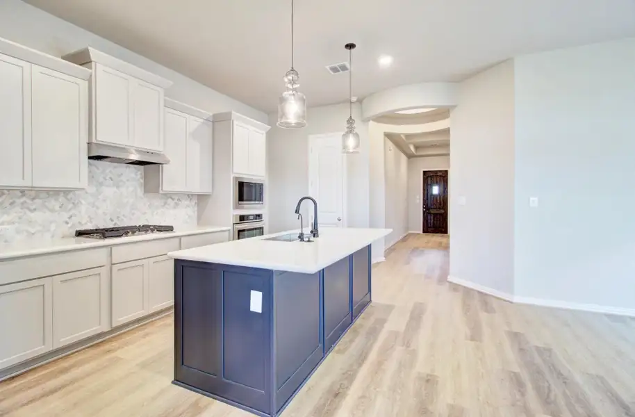 Kitchen with backsplash, hanging light fixtures, white cabinets, light wood-type flooring, and recessed lighting Kitchen with backsplash, hanging light fixtures, white cabinets, light wood-type flooring, and recessed lighting
