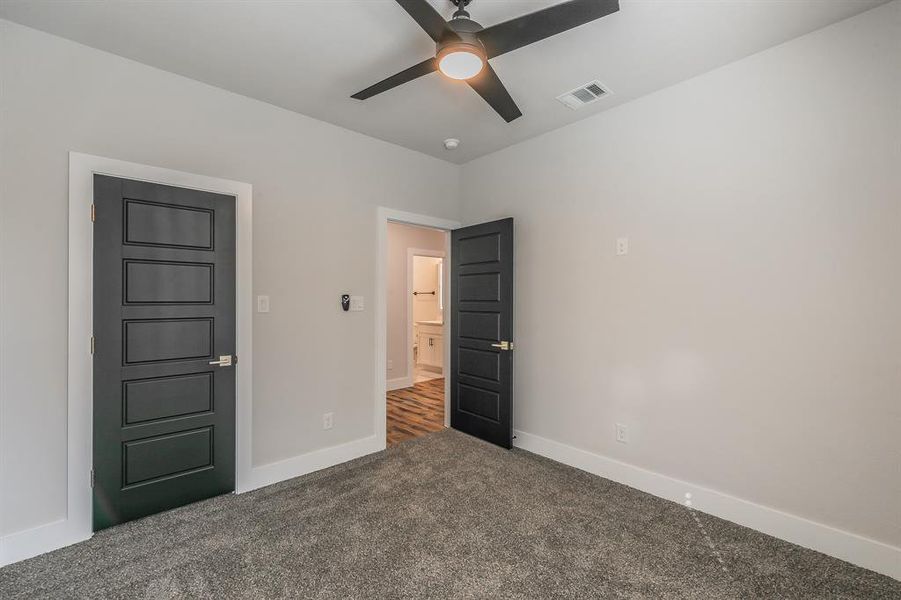 Unfurnished bedroom featuring dark colored carpet and ceiling fan