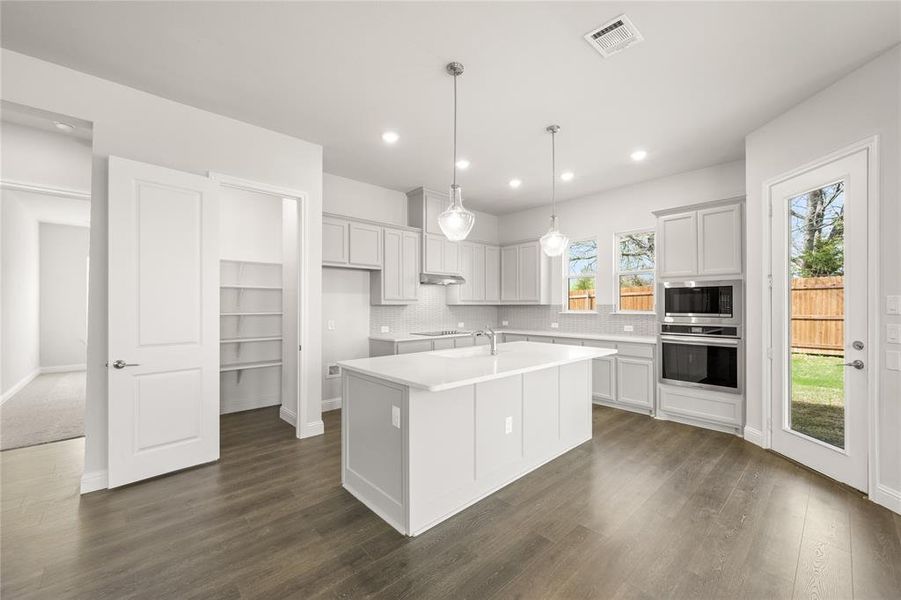 Spacious Kitchen with stainless steel appliances, island dark wood-style floors, recessed lighting, and sleek backsplash Spacious Kitchen with stainless steel appliances, island dark wood-style floors, recessed lighting, and sleek backsplash