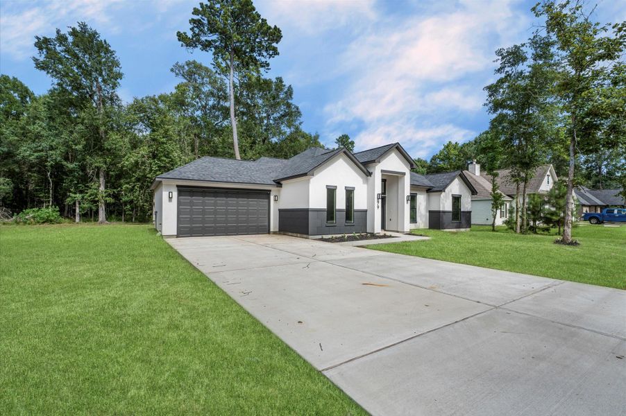 Modern single-story home with a clean, elegant exterior. Features a spacious driveway leading to an attached two-car garage. Surrounded by lush greenery, offering a serene and private setting. Modern single-story home with a clean, elegant exterior. Features a spacious driveway leading to an attached two-car garage. Surrounded by lush greenery, offering a serene and private setting.